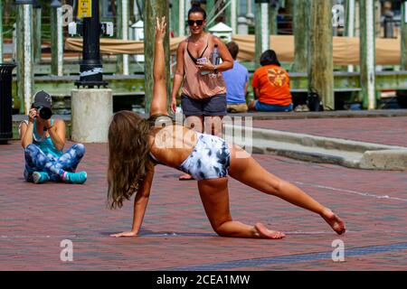 Annapolis, MD 08/21/2020: A teen gymnast girl in swimsuit  is posing to a professional photographer on cobblestone ground of Annapolis Marina  Mother Stock Photo
