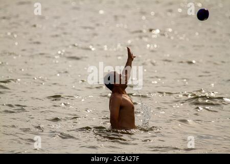Rock Hall, MD 08/22/2020: A young caucasian man is playing a ball game in Chesapeake bay. He is jumping to reach to the ball and catch it. He is athle Stock Photo