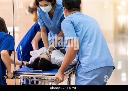 Medical team do CPR Cardiopulmonary resuscitation to seriously injured patient with oxygen mask while push gurney stretcher bed to Operating Room. Eme Stock Photo
