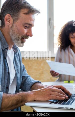 man using laptop near chatting colleagues Stock Photo