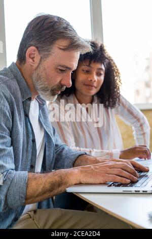 man using laptop near chatting colleagues Stock Photo