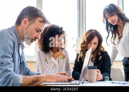 man using laptop near chatting colleagues Stock Photo