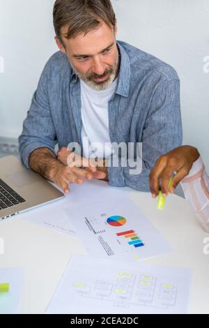 Bearded office worker discussing diagrams with colleague Stock Photo