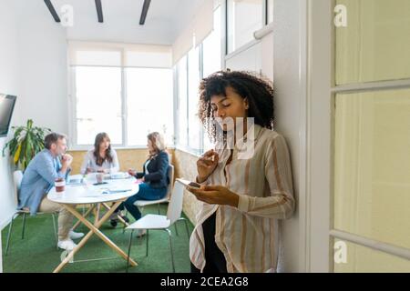 Attractive african-american female using smartphone in conference room with workers Stock Photo