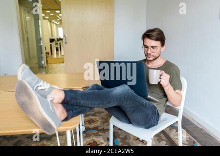 Young man sitting in office with laptop Stock Photo