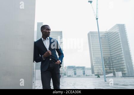 African-American businessman leaning on wall outdoors Stock Photo