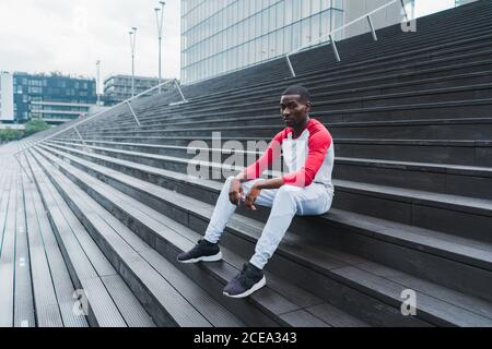 Ethnic male resting on stairs after workout Stock Photo