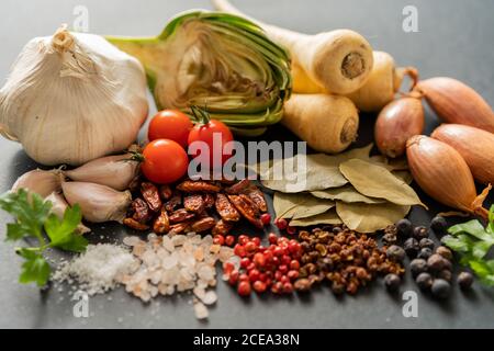 Bunch of assorted ripe vegetables and dried spices lying on gray background Stock Photo