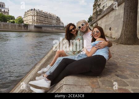 Friends sitting together on waterfront Stock Photo