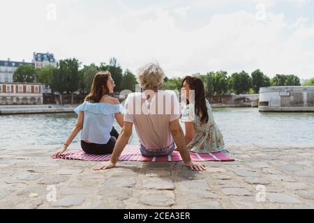 Friends sitting together on waterfront Stock Photo