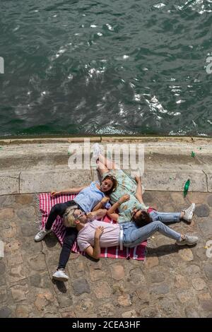 Friends lying on blanket on waterfront Stock Photo