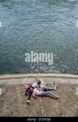 Friends lying on blanket on waterfront Stock Photo