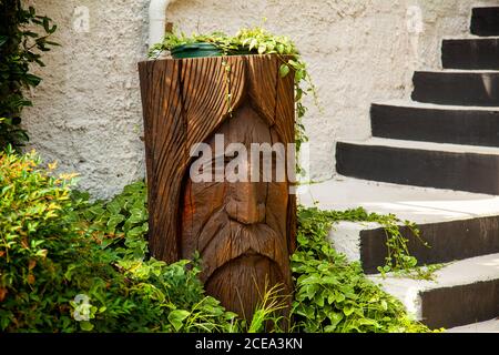 Annapolis, MD 08/21/2020: A garden with with stone stairs and a wooden log used as a pot holder. The wood is carved into the impression of an old man' Stock Photo