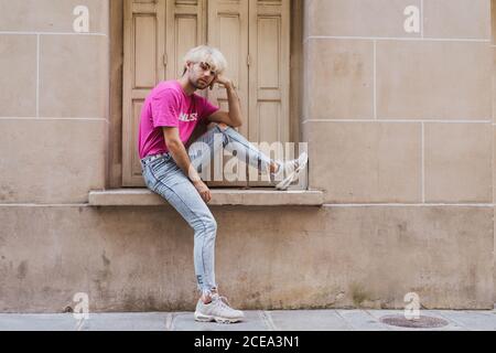 Stylish man sitting on window sill Stock Photo