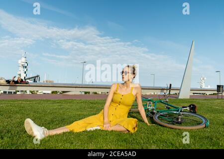 Woman sitting on grass with bicycle Stock Photo