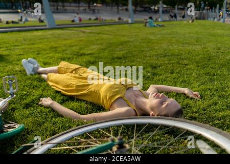 Woman lying on grass with bicycle Stock Photo