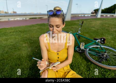 Woman sitting on grass with bicycle Stock Photo