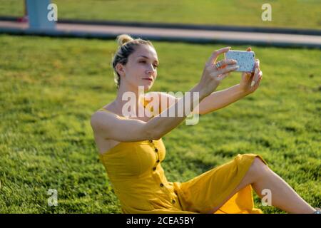 Woman sitting on grass with smartphone Stock Photo