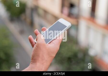 Crop male hand holding and using smartphone on street Stock Photo