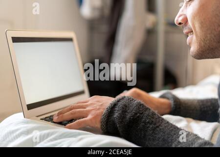man chilling on bed with laptop Stock Photo