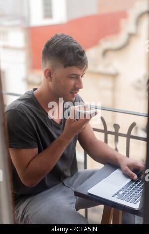 man speaking on phone and using laptop Stock Photo