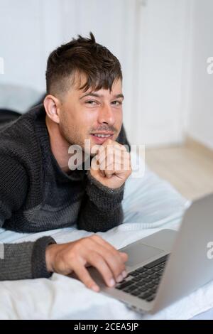 man chilling on bed with laptop Stock Photo