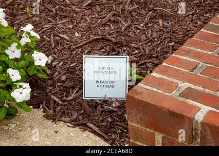 Close up image of a funny and creative yard sign placed among wood chips on the front yard of a house that reads: This is a Private Sign, Do not Read. Stock Photo