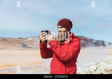 man standing with smartphone at geyser Stock Photo