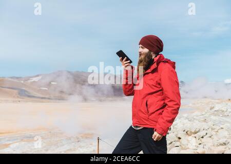 man standing with smartphone at geyser Stock Photo