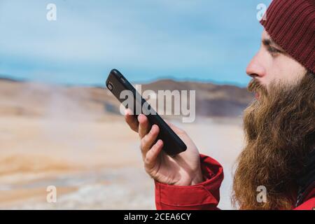 man standing with smartphone at geyser Stock Photo