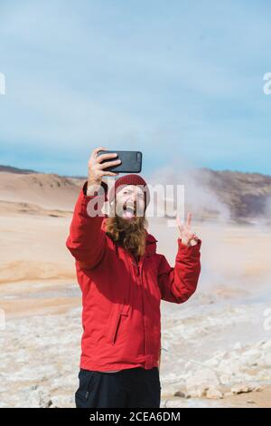 man standing with smartphone at geyser Stock Photo