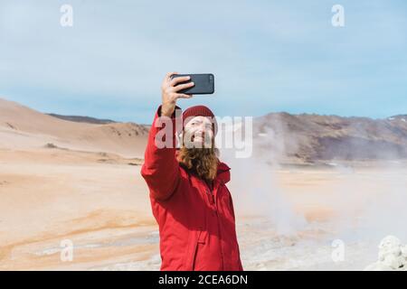 man standing with smartphone at geyser Stock Photo