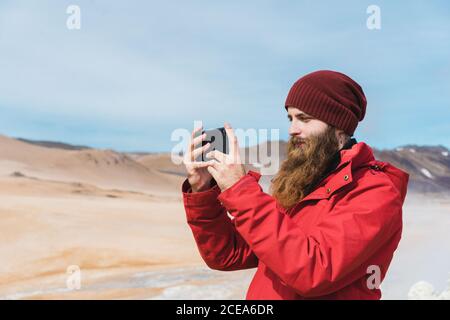 man standing with smartphone at geyser Stock Photo