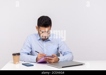 Busy inspired man employee writing creative idea paper notebook, preparing report doing paperwork, journalist taking notes in his office workplace. in Stock Photo