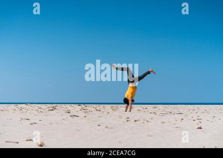 Side view of bearded man falling to sand on beach at the ocean. Stock Photo