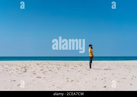 Side view of bearded man falling to sand on beach at the ocean. Stock Photo