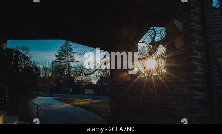 The Sun Shining Through a Window in a Cobblestone Wall in a Suburban Neighborhood Stock Photo