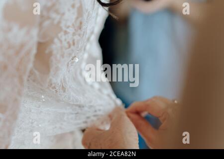 Crop Woman helping bride with corsage Stock Photo