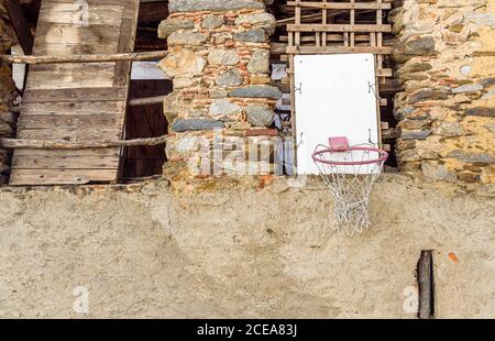 Basketball ring hanging on a rustic wall of the rural house Stock Photo