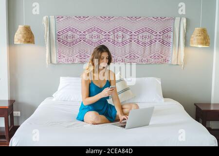 Woman using smartphone on bed Stock Photo