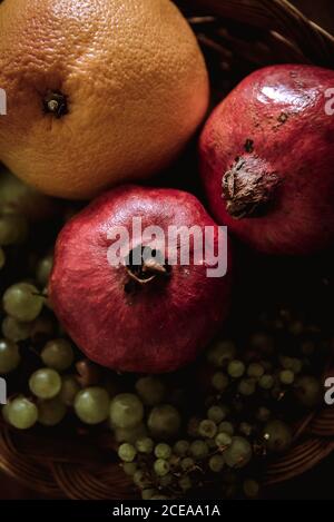 Composition of basket with oranges, grapes and pomegranates on table Stock Photo