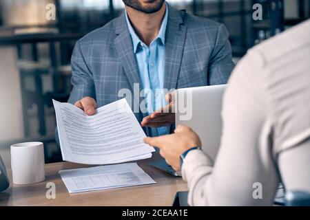 Two businessmen sitting in office with paper agreement in hands Stock Photo