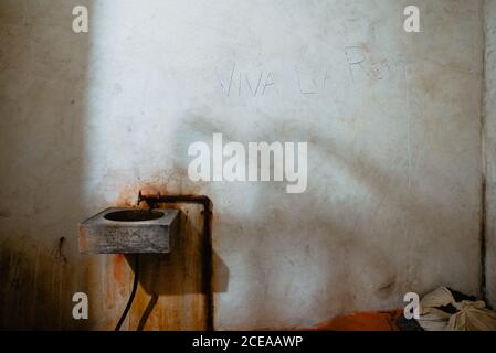 Dirty sink attached to shabby concrete wall of old cell of jail in Oviedo, Spain Stock Photo