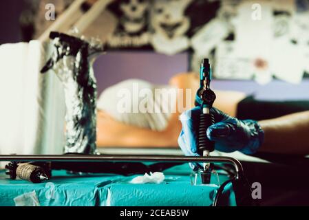 Hand of anonymous tattoo artist taking ink with professional machine while working in studio Stock Photo