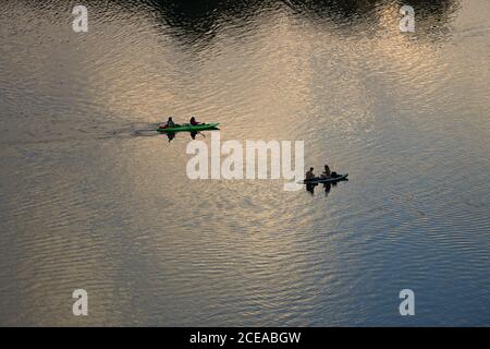Austin, Texas, USA, Aug. 18, 2020: A couple sitting on a stand-up paddle board and paddlers in a kayak enjoy sunset after a hot summer day on Lady Bird Lake in downtown Austin. ©Bob Daemmrich Stock Photo