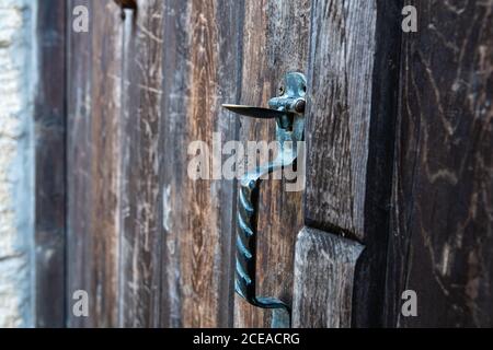 Vintage metal iron door handle on an old door made of natural wood. Horizontal orientation, selective focus. Doorknocker Stock Photo
