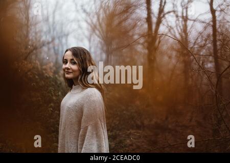 Side view of smiling attractive Woman standing in autumn forest. Stock Photo