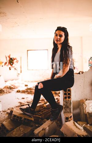 young Woman sitting in derelict building looking at camera Stock Photo