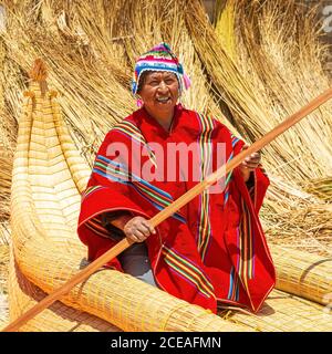 Bolivian Aymara indigenous man with traditional clothing in its traditional Totora Reed boat, Titicaca Lake, Bolivia. Stock Photo