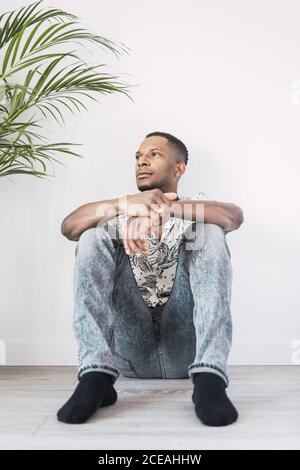 Pensive black man on ground looking away Stock Photo